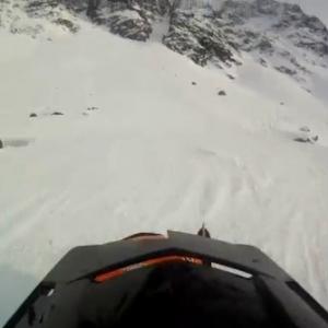 Homem bate snowmobile e desce rolando a montanha.