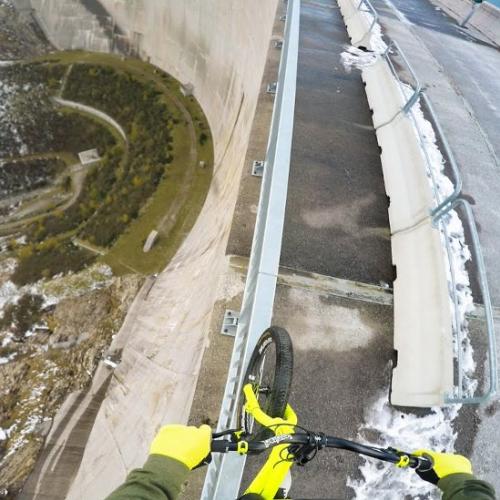 Andando de bicicleta pelo corrimão de uma barragem a 200 metros de alt