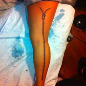 Modelo tatua zíper gigante na perna 